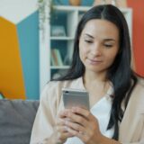 スマートフォンを手に持って画面を確認する女性のイメージ写真