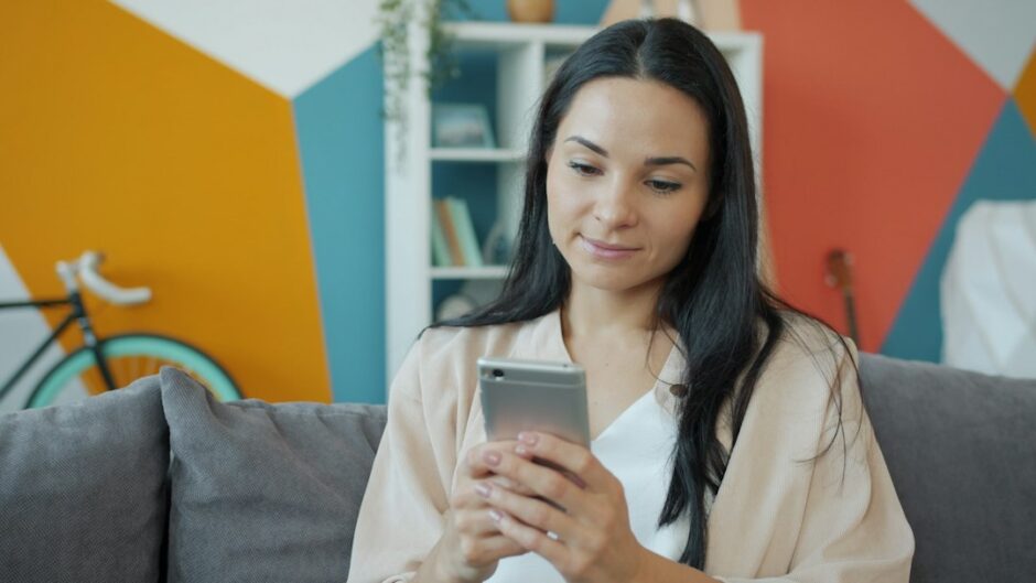 スマートフォンを手に持って画面を確認する女性のイメージ写真