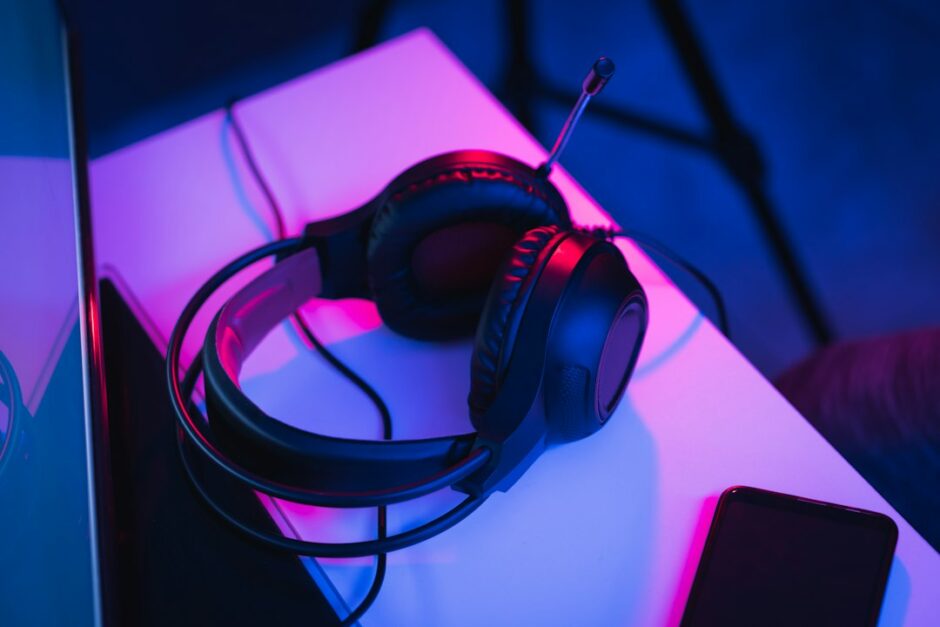ヘッドセットをつけてオンラインで話しながらゲームをする人（ゲームチャットのイメージ）