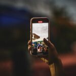 スマートフォンで写真を撮影する人。写真を残しながら本体のストレージを整理するイメージ