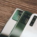 木のテーブルに並んだ2台のスマートフォン。古いスマホから新しいスマホへのデータ移行のイメージ
