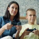 保護者と子どもがゲームのコントローラーを持って遊んでいる様子