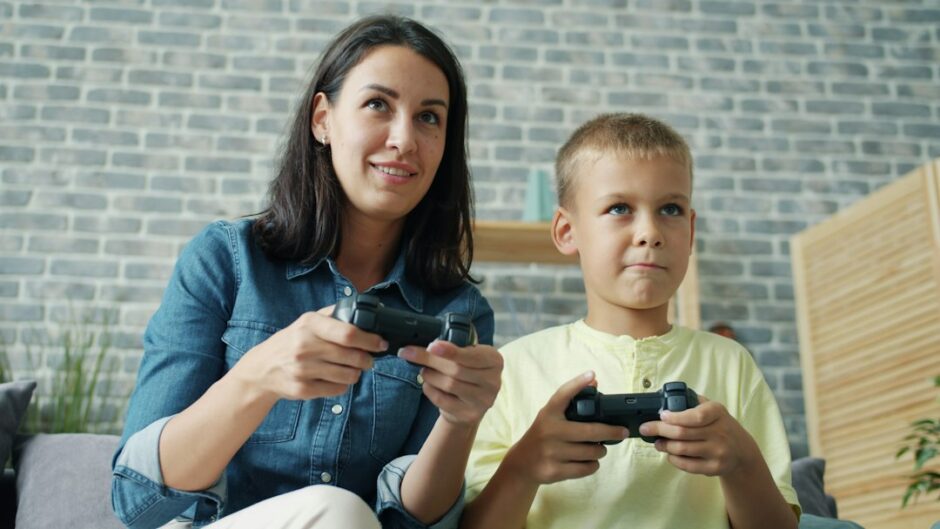 保護者と子どもがゲームのコントローラーを持って遊んでいる様子